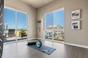 A yoga mat is on the floor in a room with a view of the city.